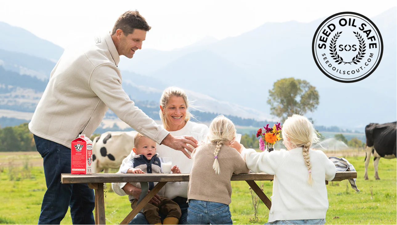 Family at a picnic table with cows in the background and a pioneer pastures carton of milk, featuring a 'Seed Oil Safe' logo.