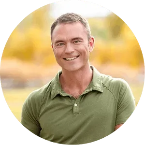 Robb Wolf wearing a green shirt with a blurred natural background